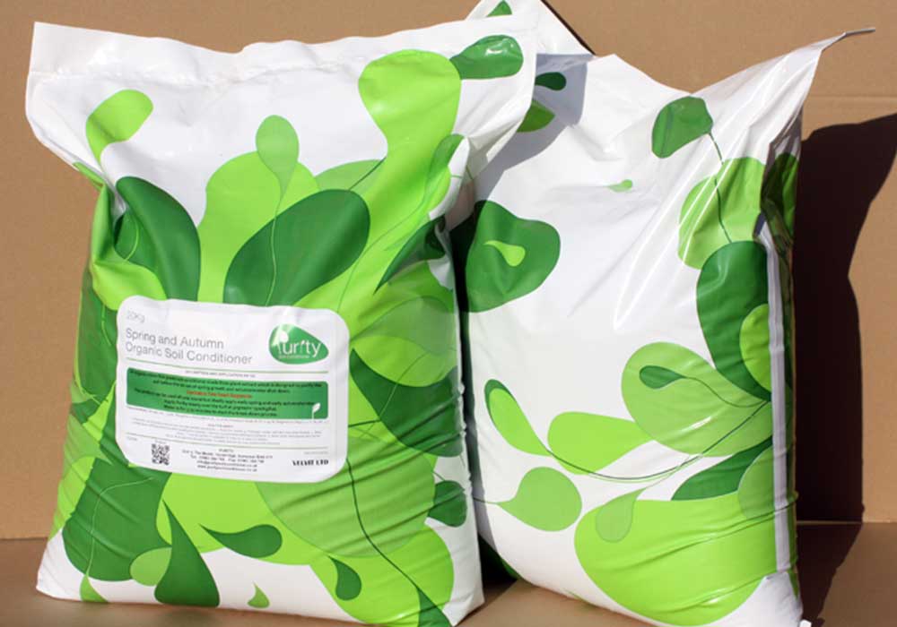 Two bags of Purity with a green pattern on them. Side by side on light brown ground